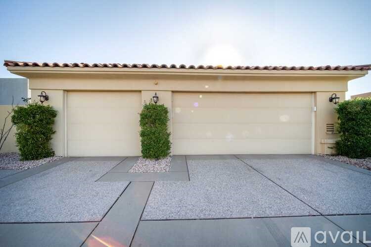 A house with a tan garage door and a small garden in front.