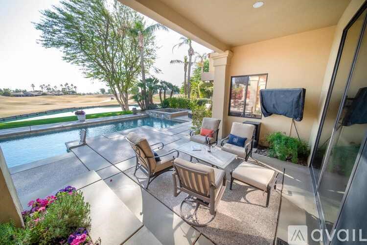 A patio with a table and chairs overlooking a pool.
