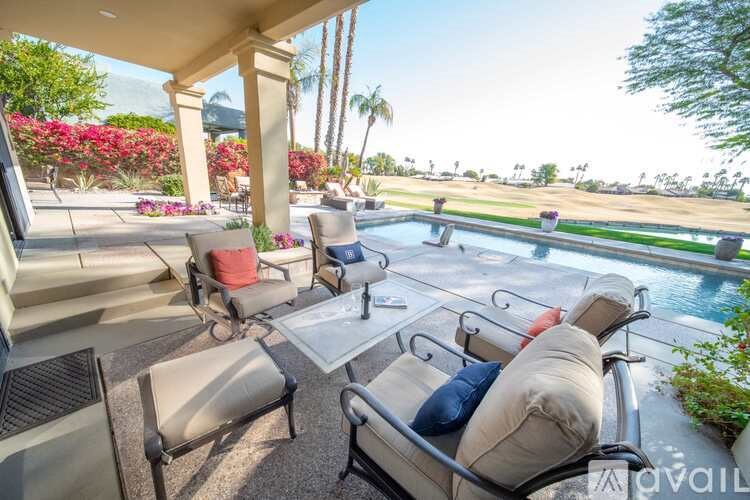 A patio with a table and chairs overlooking a pool.