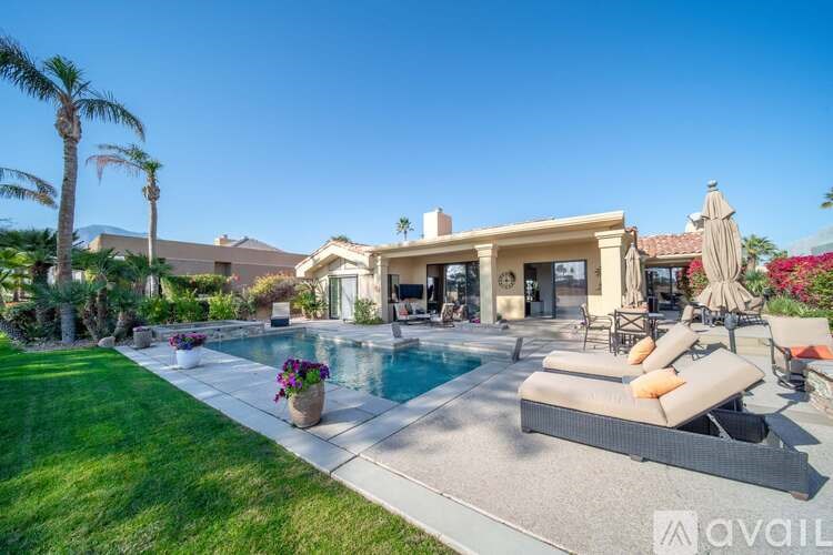 A large house with a pool and lounge chairs.