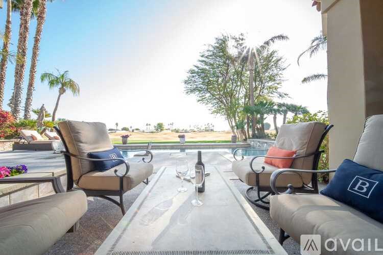 A table with two chairs and a bottle of wine on it.