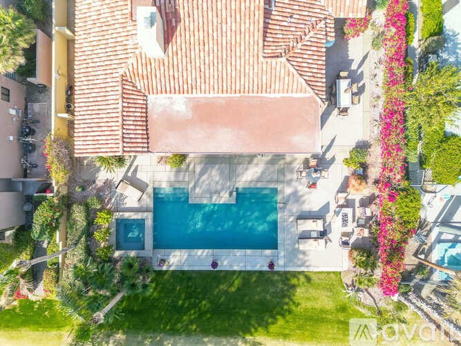 A house with a red tiled roof and a blue pool in the backyard.