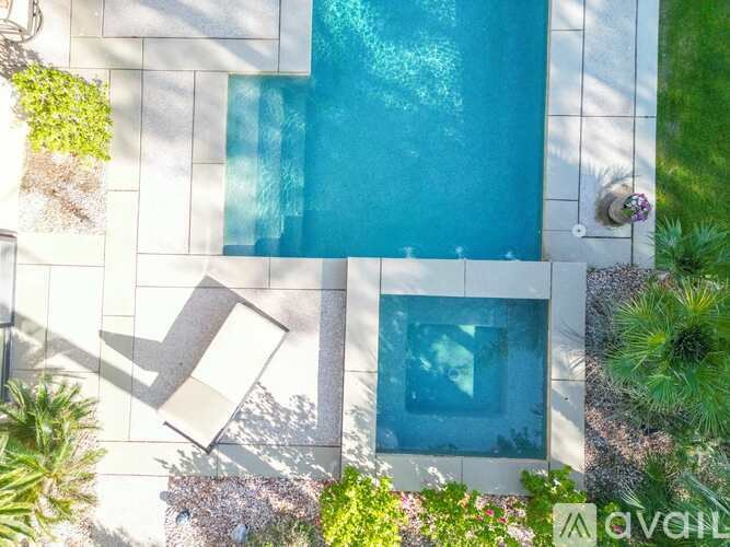 A pool surrounded by a white tiled wall and green plants.