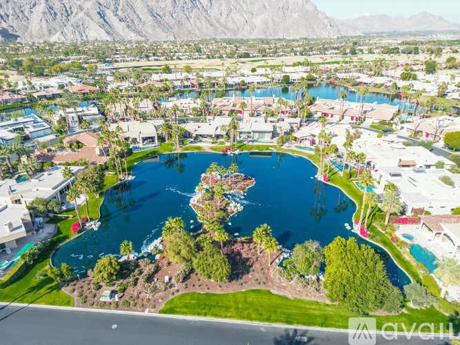A large swimming pool surrounded by palm trees and a mountain range in the background.