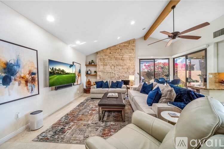 A living room with a stone wall and a ceiling fan.