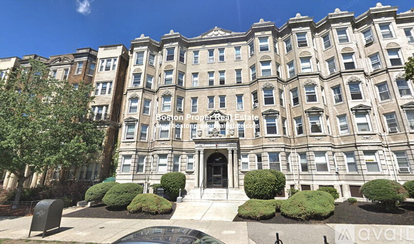 A large, multi-story building with a central entrance and a balcony above the doorway.