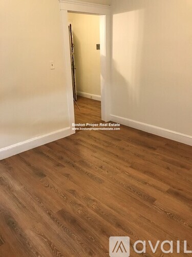 A room with wooden flooring and white walls.