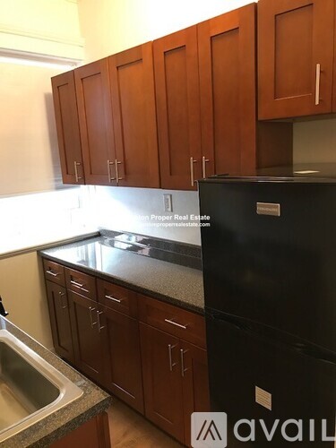 A kitchen with wooden cabinets and a black fridge.
