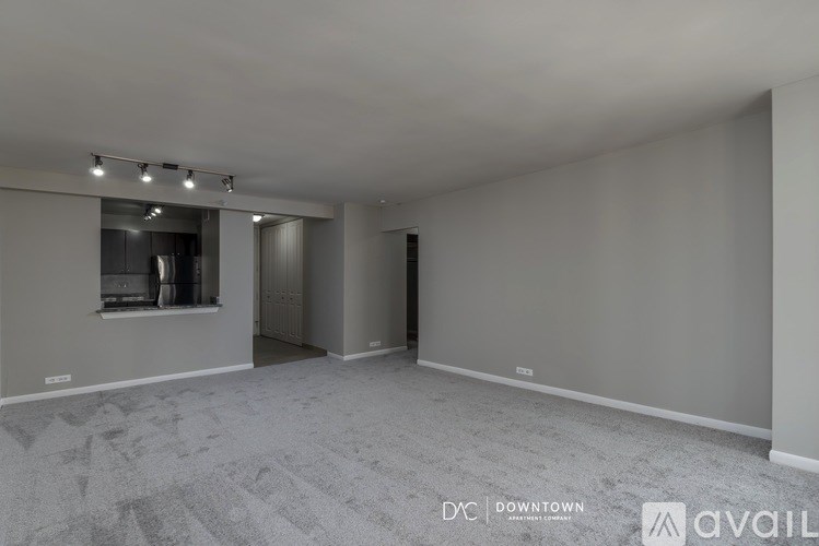 A spacious room with a carpeted floor and a window with blinds.