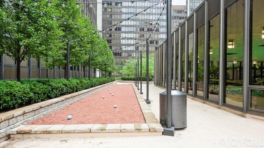 A red brick pathway leads through a landscaped area between two buildings.