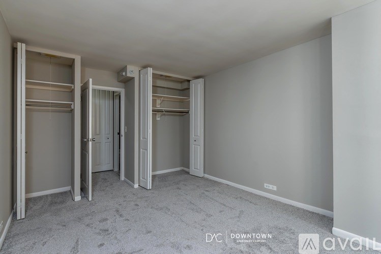 A room with white walls and a carpeted floor with a row of closets on the left side.