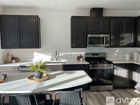 A modern kitchen with black cabinets and stainless steel appliances.