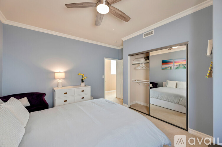 A bedroom with a large bed and a mirrored closet door.