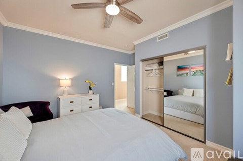 A bedroom with a large bed and a mirrored closet door.