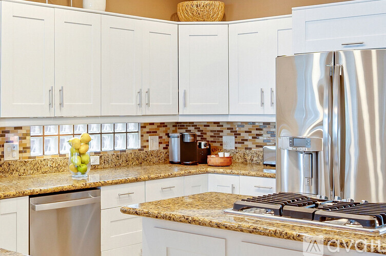 A kitchen with a stainless steel refrigerator and a granite countertop.