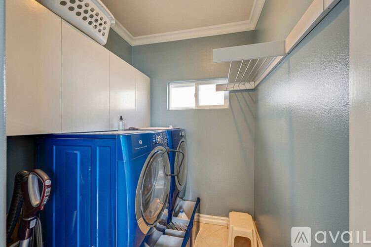 A small laundry room with a blue washing machine and a window.