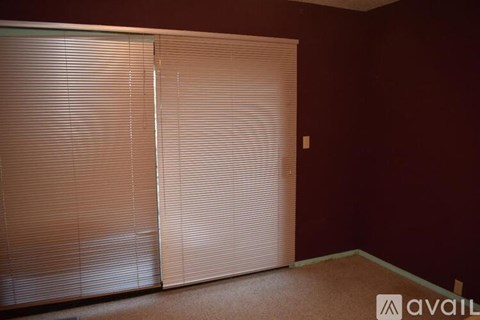 A room with a pair of closed blinds on the window.