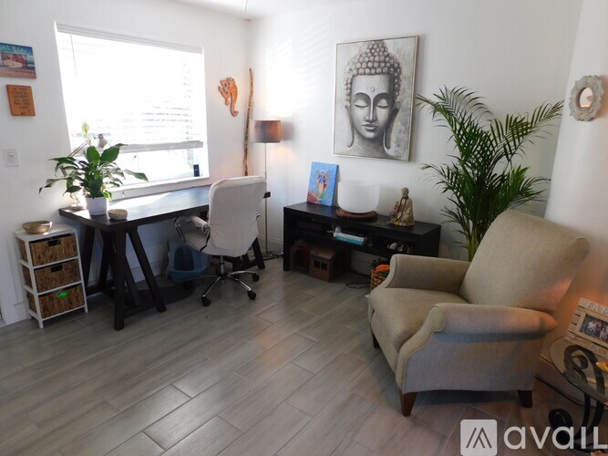 A room with a white chair, a desk with a computer, and a plant.