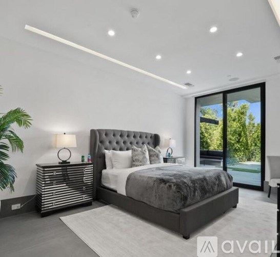 A bedroom with a large bed and a sliding glass door.
