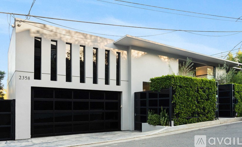 A modern house with a white facade and black garage doors.