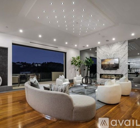 A modern living room with a large grey sofa and a fireplace.