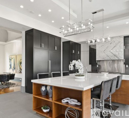 A modern kitchen with a large island and black cabinets.