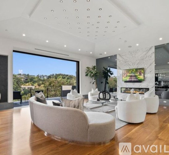 A modern living room with a large window overlooking a tree-filled landscape.