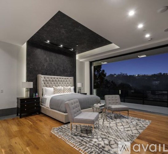 A bedroom with a large bed and a chair in front of a window.