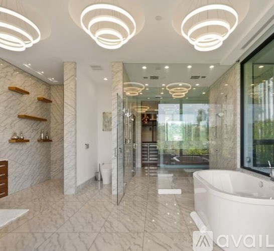 A bathroom with a tub, sink, and marble floors.