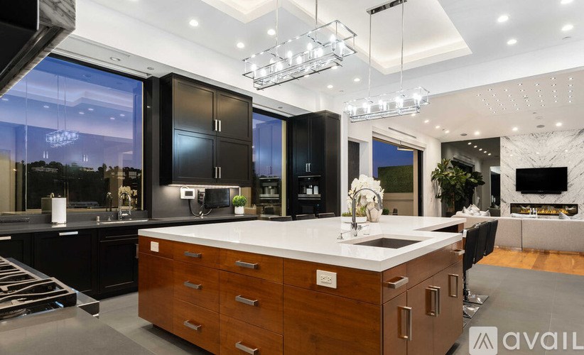A modern kitchen with a large island and a view of the city at night.