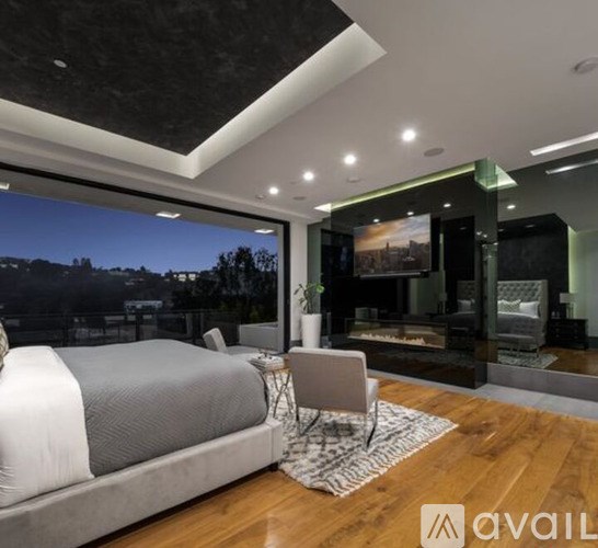 A bedroom with a large bed and a view of the city at night.