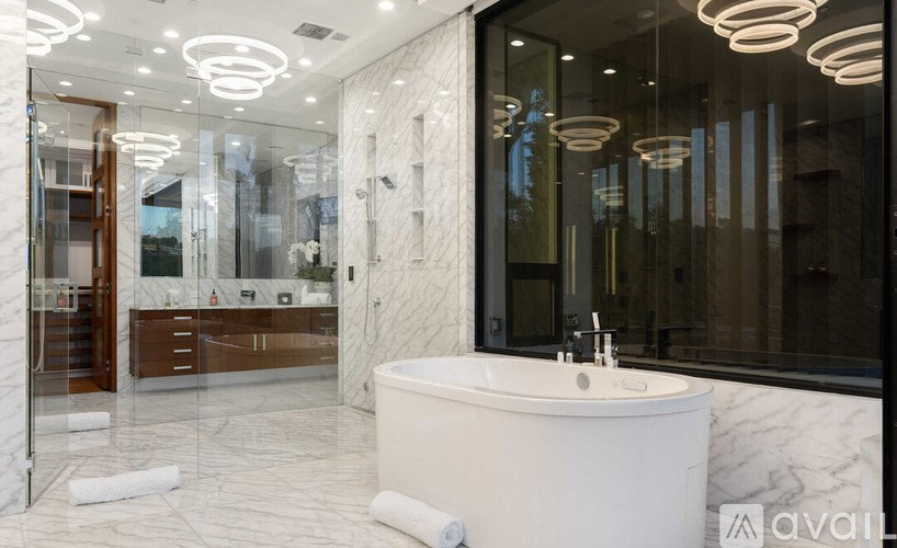 A modern bathroom with a white marble tub and a glass shower.