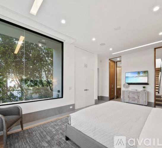 A bedroom with a large bed and a flat screen TV mounted on the wall.