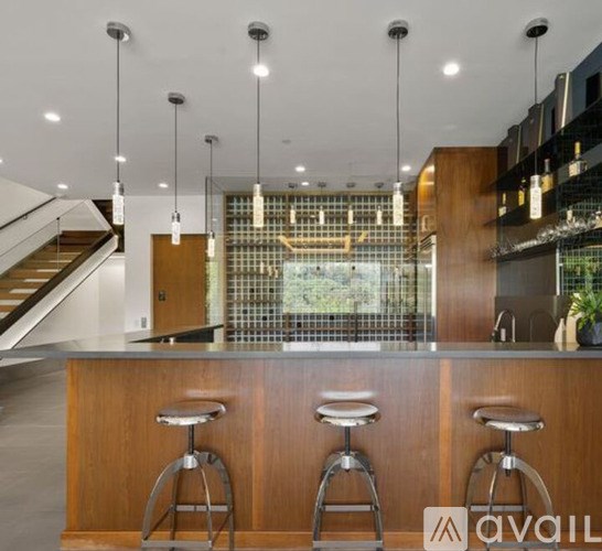 A modern bar with three stools and a glass partition in the background.