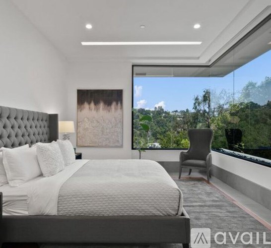 A bedroom with a large bed and a view of the outdoors through a window.