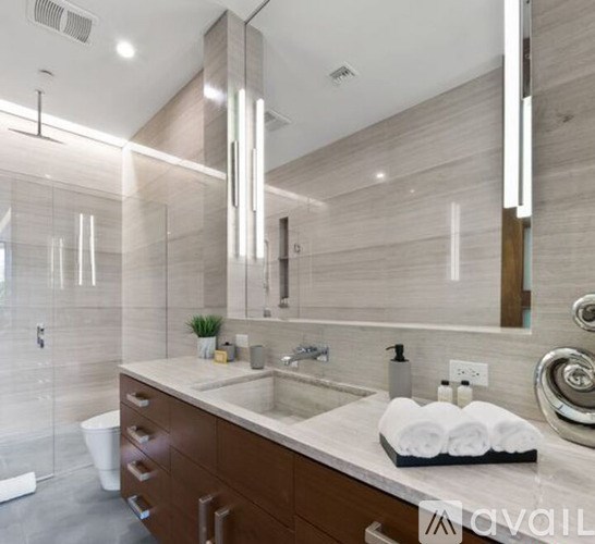 A modern bathroom with a marble countertop and a large mirror.