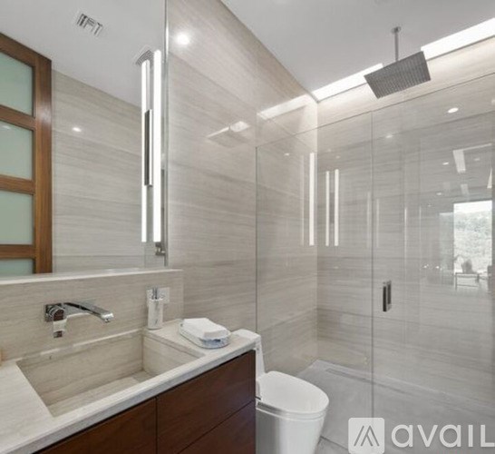 A modern bathroom with a glass shower stall and a white toilet.