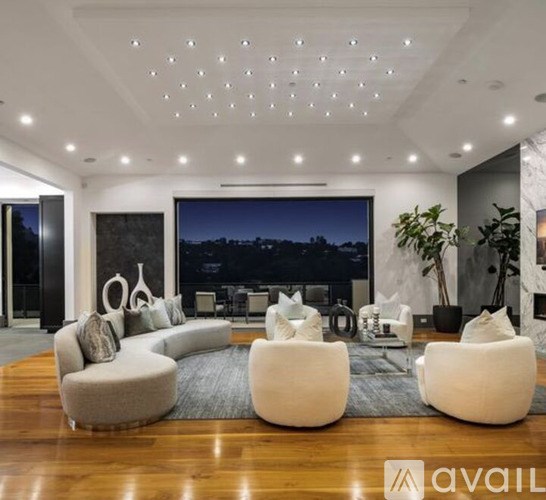 A modern living room with a large window overlooking the city at night.