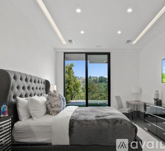 A bedroom with a large bed and a view of trees outside the window.