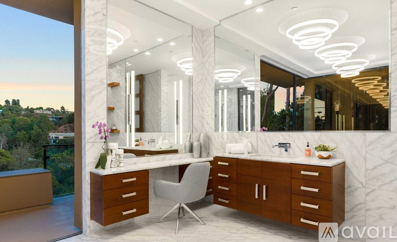 A modern bathroom with a large mirror and a chair.