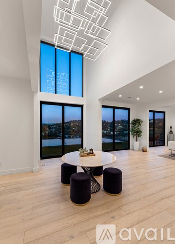 A modern living room with a round table and black ottomans.