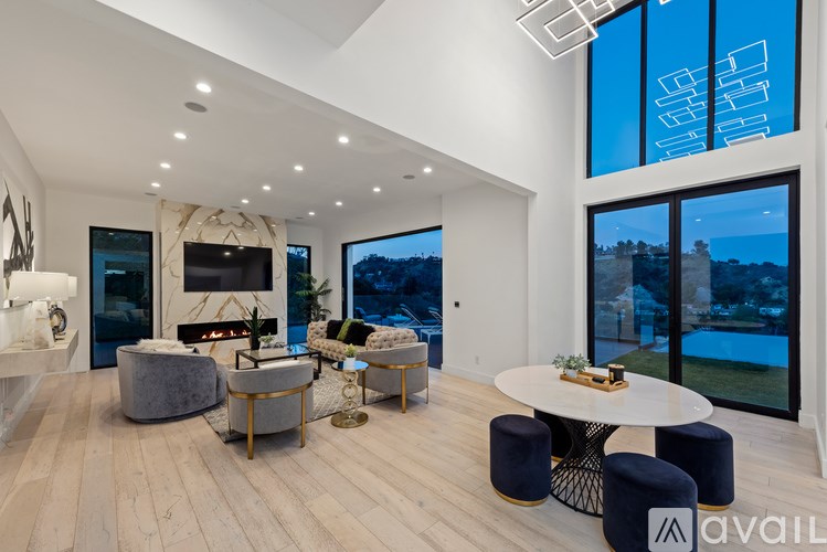 A modern living room with a fireplace and a view of the pool outside.