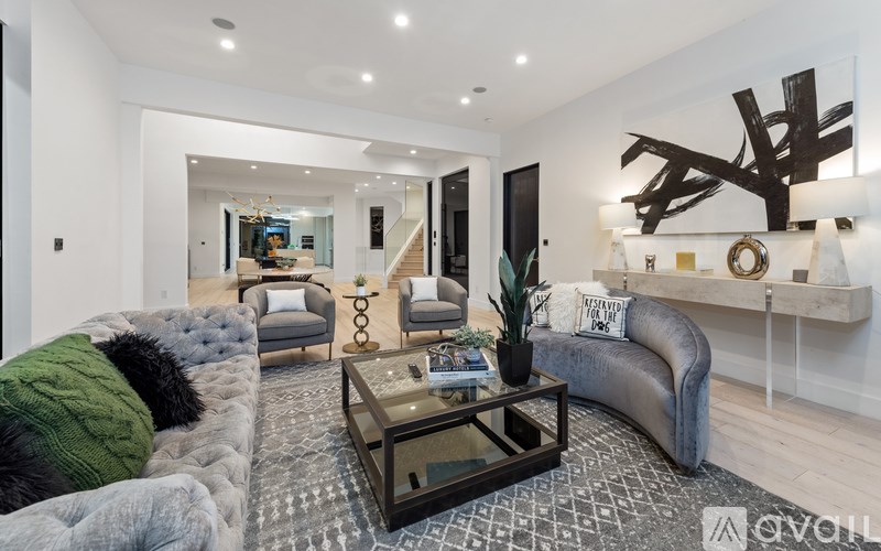 A living room with a grey couch and a glass coffee table.