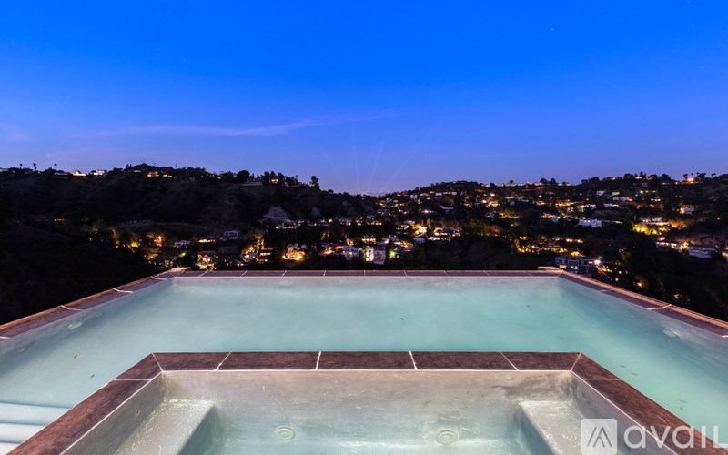 A swimming pool with a view of a city at night.