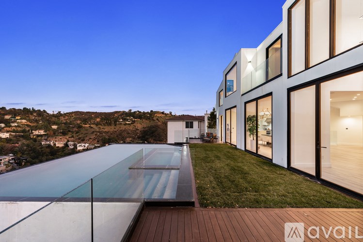 A modern house with a glass wall and a wooden deck.