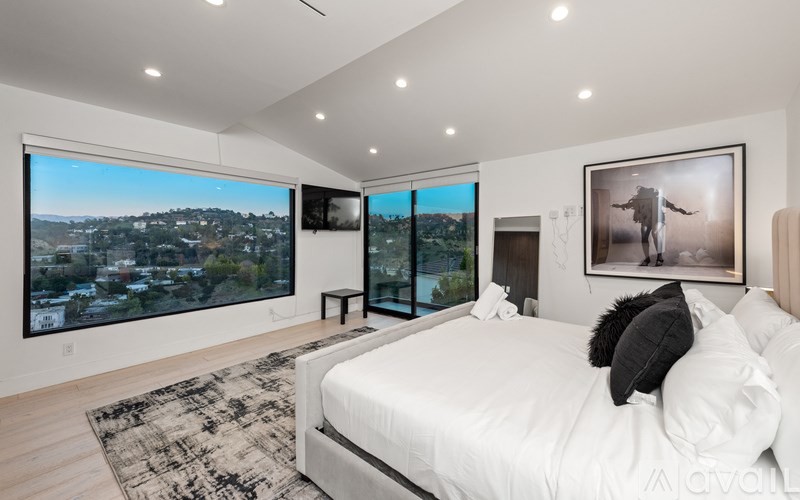 A bedroom with a large bed and a view of the city through the windows.
