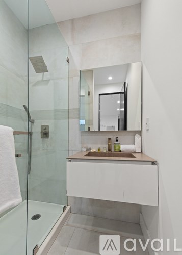 A bathroom with a glass shower stall and a white vanity.