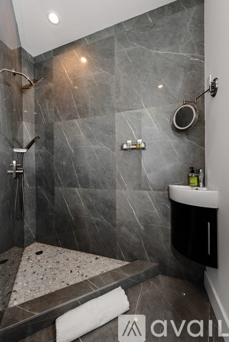 A bathroom with a marble wall and a round mirror.