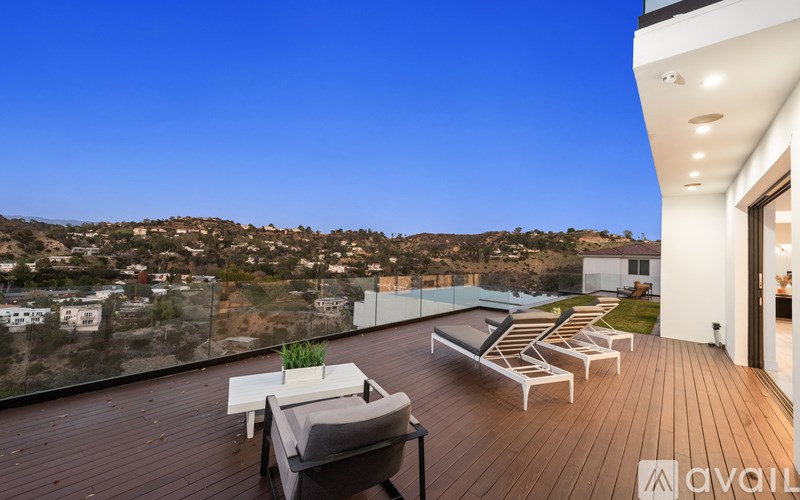 A wooden deck with lounge chairs overlooks a hillside town.