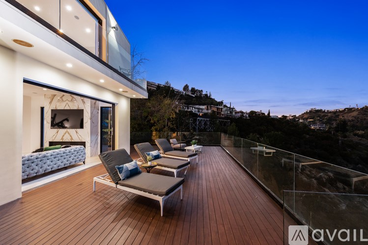 A modern house with a deck and lounge chairs.